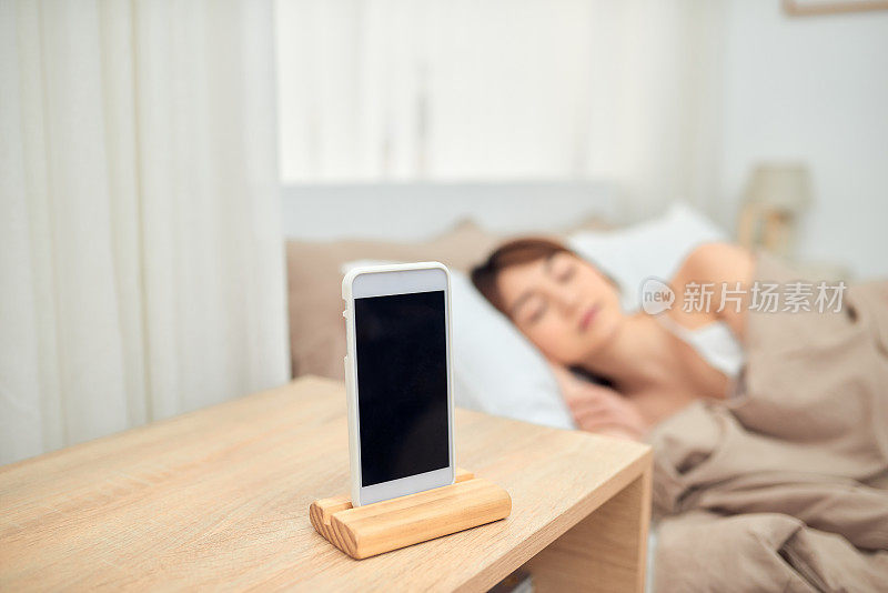 亚洲女性在床上睡觉时被手机闹铃吵醒