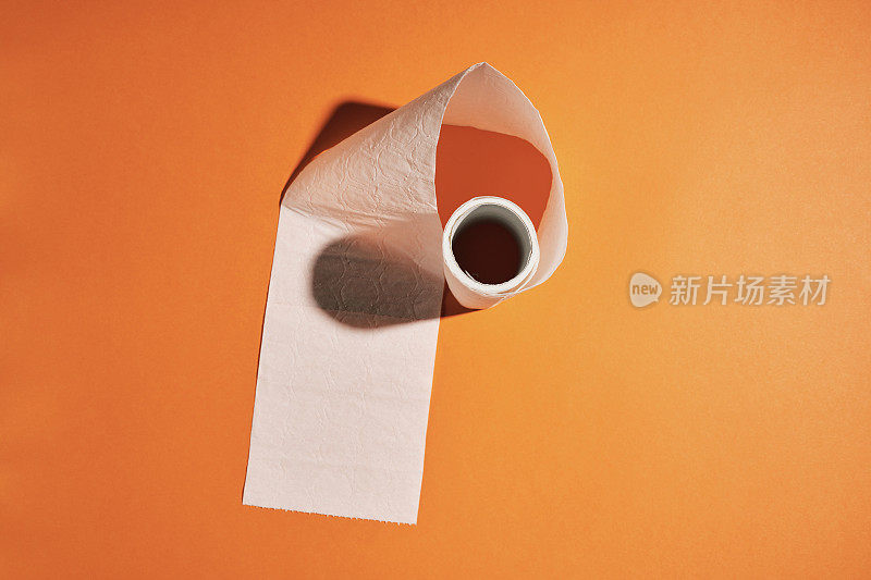 几乎空无一物的厕纸映衬着明亮的橙色背景。
