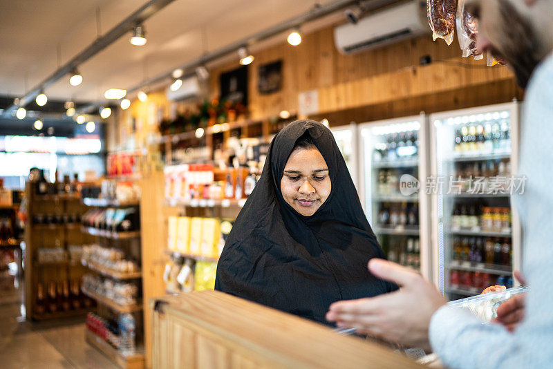 一位中东阿拉伯妇女在便利店买食物