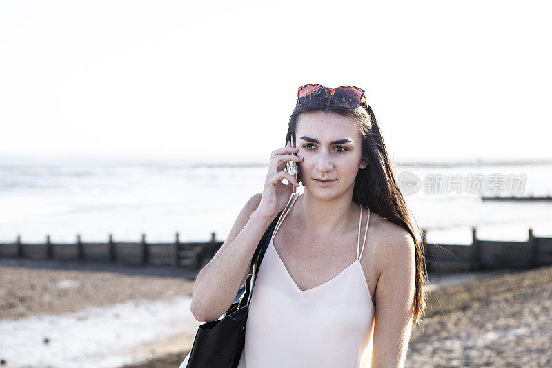 少女在海边谈论智能手机在夏天的傍晚