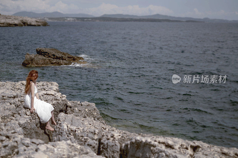 独自一人坐在岩石海岸的女人