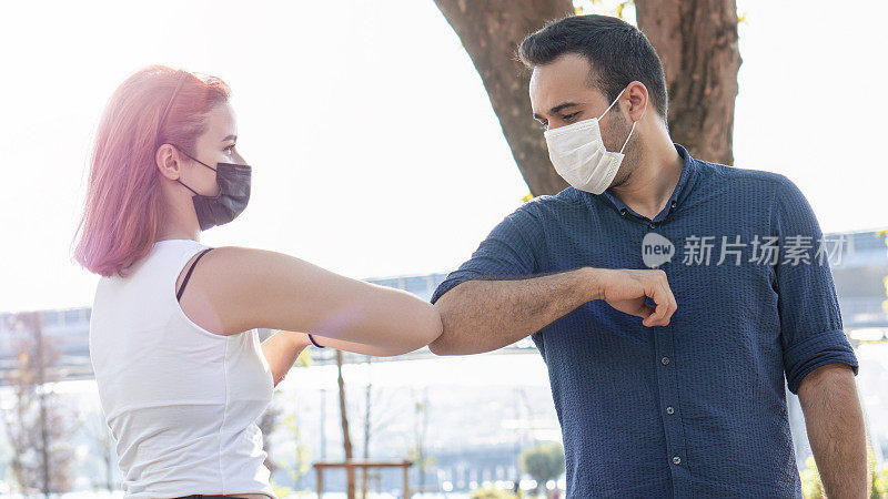 朋友们戴着外科口罩在户外练习社交距离。