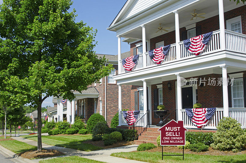 标志:必须出售:在家门口悬挂美国国旗和警告金融危机的彩旗