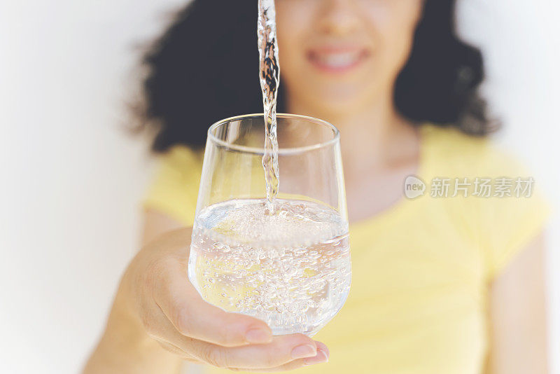 喝水。女人的手把新鲜的纯净水从水罐倒进杯子里。健康与饮食概念。健康的生活方式。医疗和美丽。Hydratation。