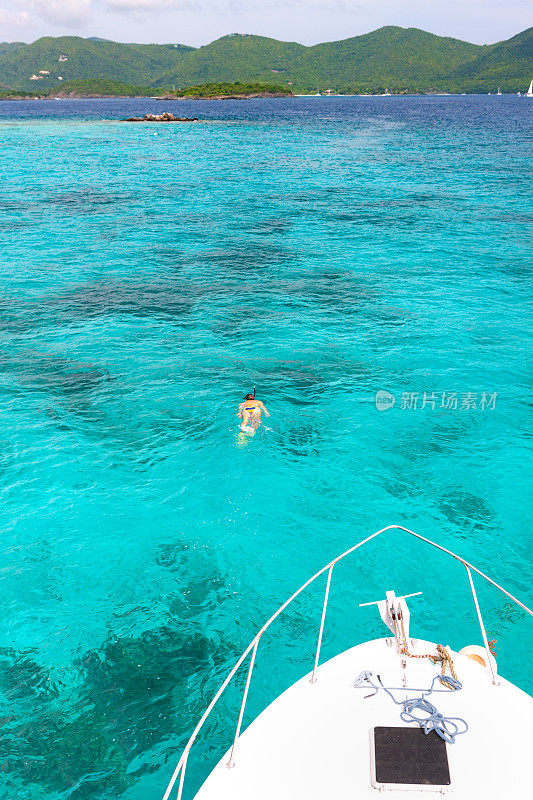 女子浮潜旁边的潜水船在维尔京群岛