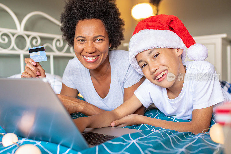 母亲和儿子享受在圣诞节假期和做网上购物