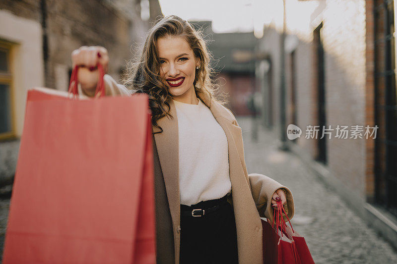 快乐的女人提着红色购物袋的肖像