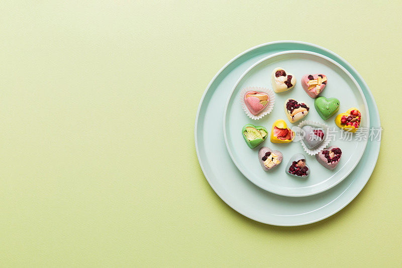 盘子与不同的巧克力在彩色背景。各种精美的巧克力俯视图与复制空间健康和肥胖的概念