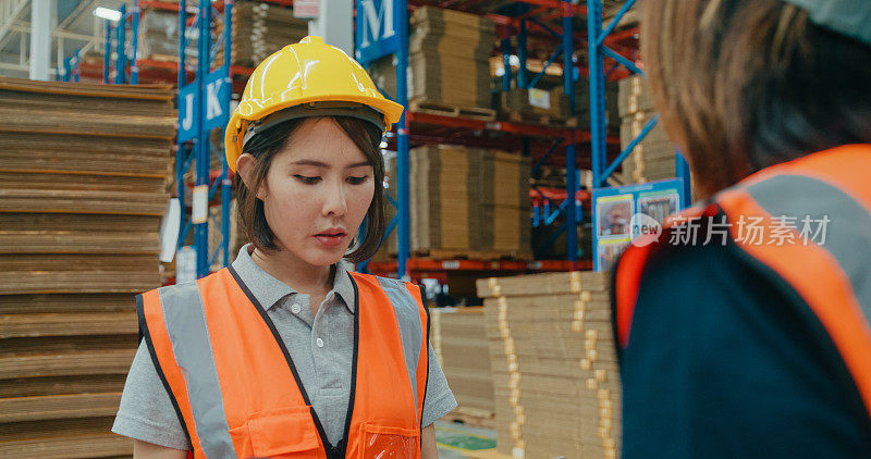 在零售仓库里，年轻的亚洲女工用平板电脑和笔记本电脑检查库存，并在一起讨论交谈。物流行业业务。