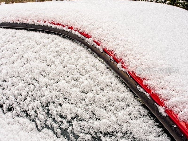 红色卡车挡风玻璃和窗户上覆盖着一层雪