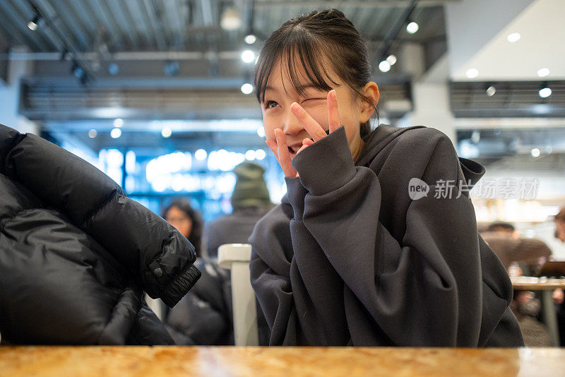 十几岁的女孩在咖啡馆等饮料-和平标志