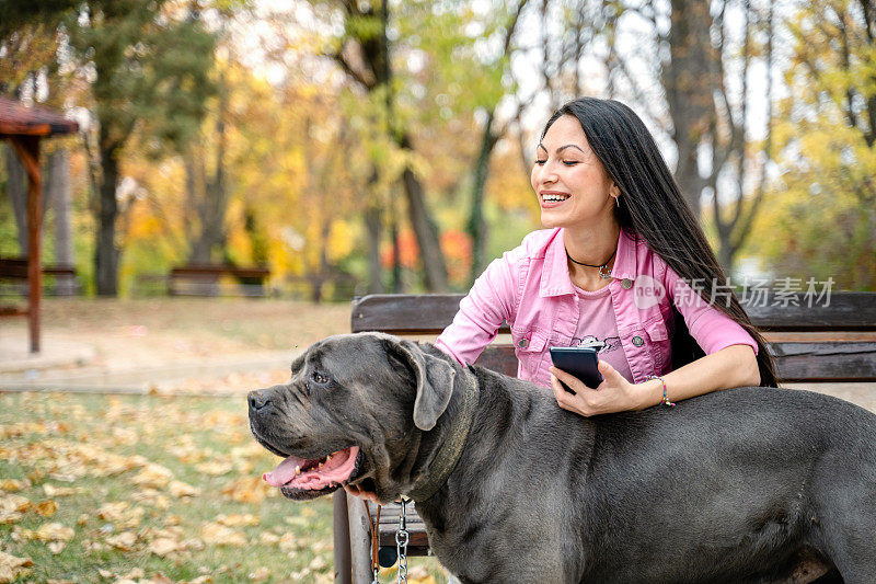 公园里的女宠物保姆和一只黑狗