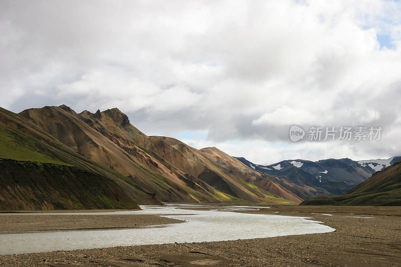 冰岛Laugevegur步道起点的Landmannalaugar周围引人注目的山景，显示了洪水平原上的冰川径流河