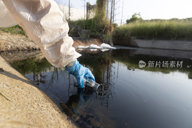 特写科学家手与白色PPE服和丁腈手套收集样品废水进入烧瓶实验室水分析，工业和环境的概念