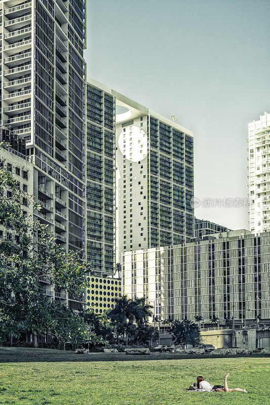 女孩在草地上学习的Brickell摩天大楼