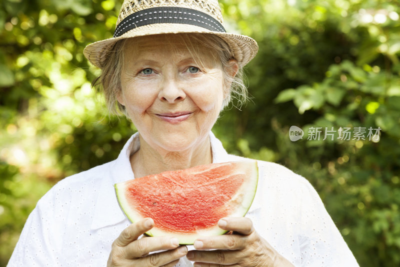 健康的老年妇女在夏天户外吃西瓜