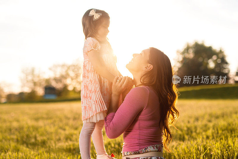 慈母和女儿在春日日落时交流。