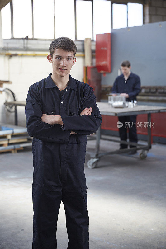 年轻的学徒穿着工装裤在钢铁厂