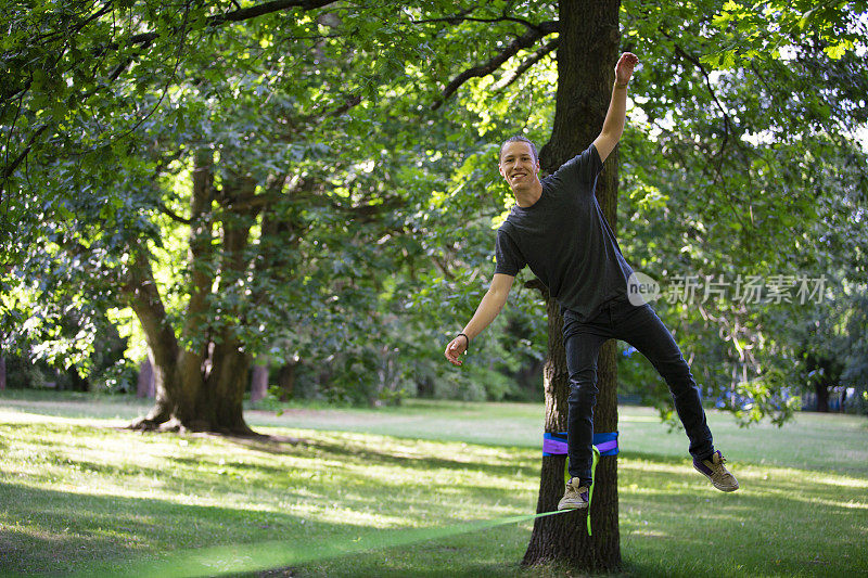 在公园里，一个年轻人在绳索上保持平衡
