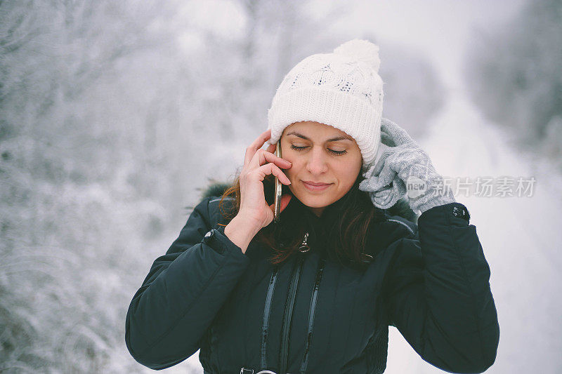 年轻美丽的黑发女子在一个下雪天打电话