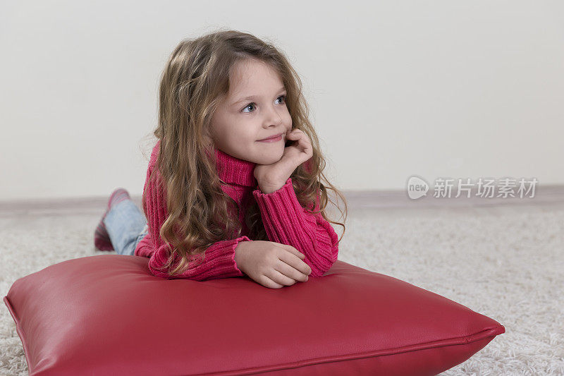 躺在红垫子上沉思的小女孩