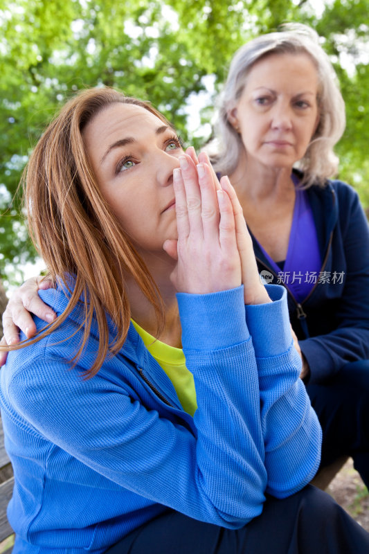 年轻女子祈祷或思考与关心的朋友在附近