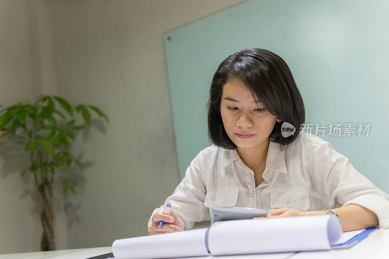 亚洲女人检查销售报告并思考