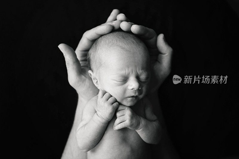 刚出生的婴儿睡在爸爸的手里
