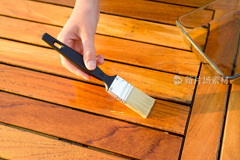 手拿刷子在花园的桌子上涂清漆