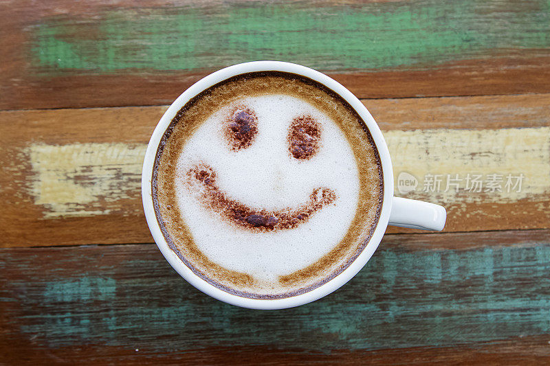 笑脸画在咖啡拉花艺术上，木色背景