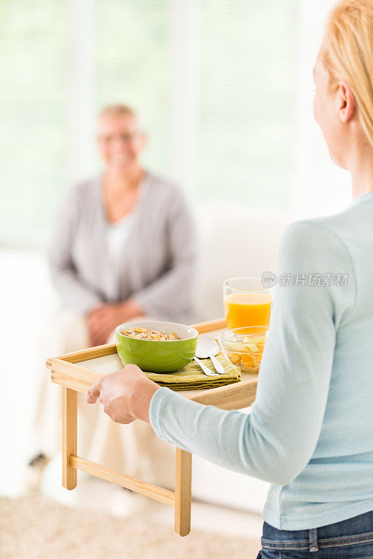 护工给一位年长的女士送早餐