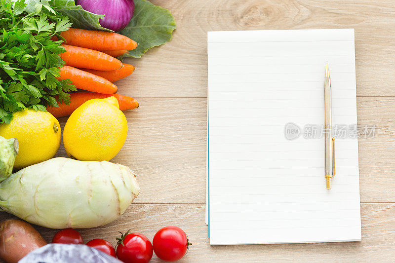 桌上放着空白的食谱和蔬菜