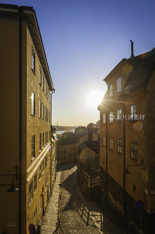 斯德哥尔摩日出的阳光闪耀在瑞典Sodermalm的鹅卵石街道上