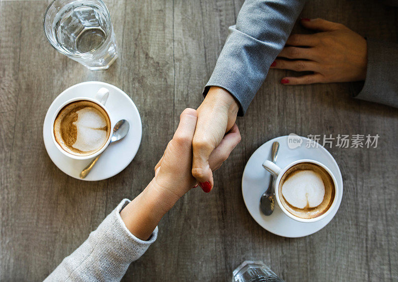 上图中，一位面目全非的女商人在咖啡馆里握手。