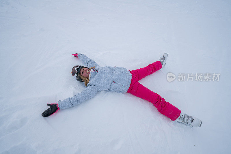 年轻女子躺在雪地上玩雪天使