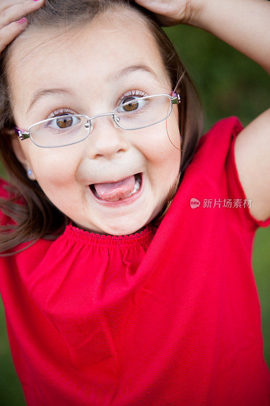 快乐的年轻女孩戴着眼镜在外面做鬼脸