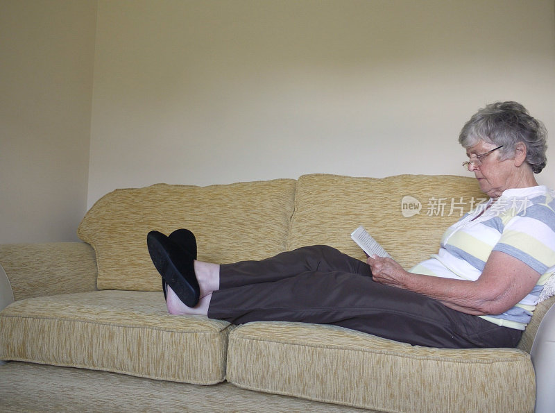 老女人，舒舒服服地躺在沙发上，看书