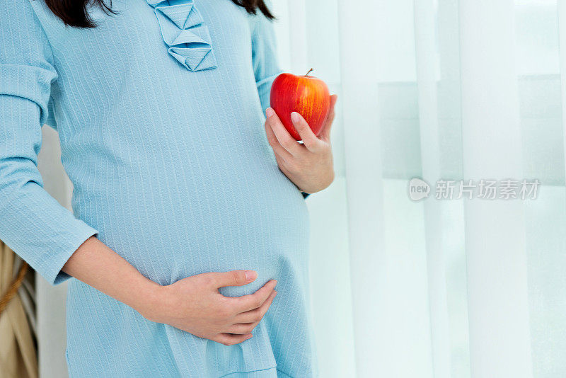 一个孕妇拿着一个红苹果