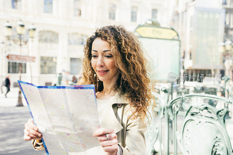 快乐的女人看着巴黎地铁站外的地图