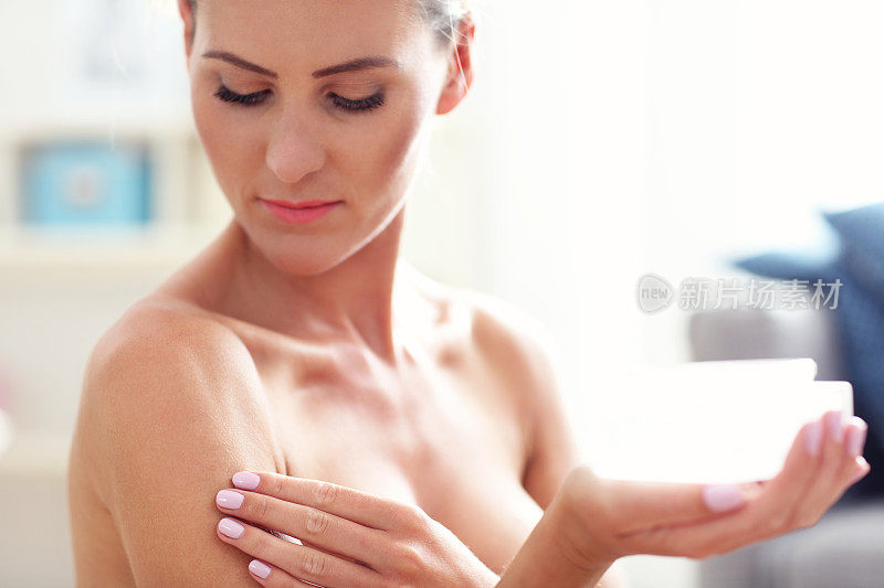 一个健康的女人在她的身体上拿乳液的照片