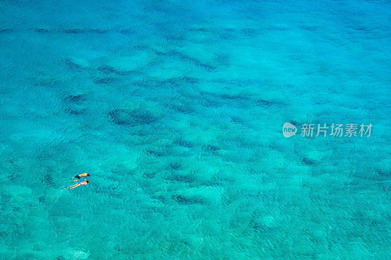 上图是一对夫妇浮潜在碧绿的海水中，格拉卡涅拉，查尼亚，克里特岛，希腊