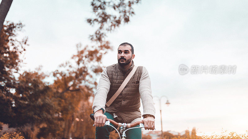 在一个美丽的秋日，一名大胡子男子骑着自行车