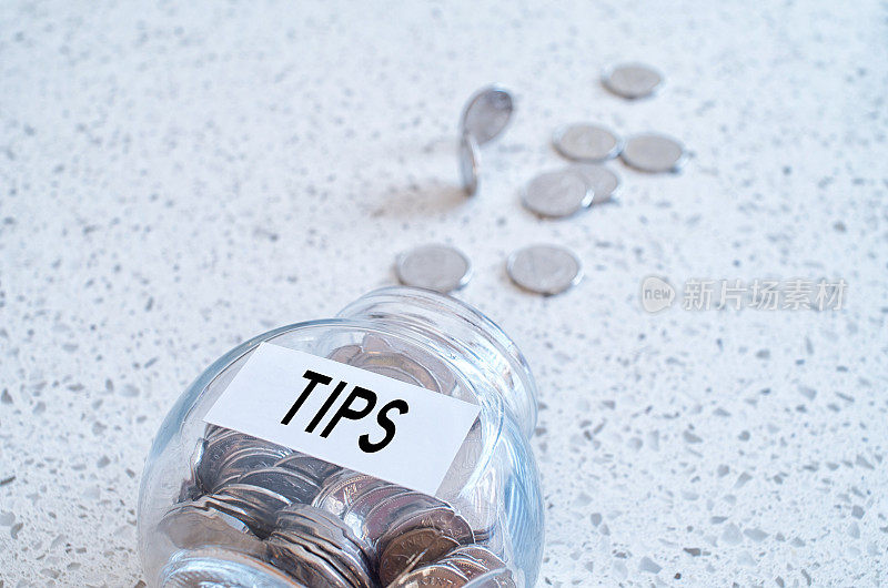 玻璃罐与许多硬币和提示字在大理石柜台上