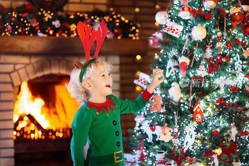 孩子在圣诞树和壁炉在圣诞夜