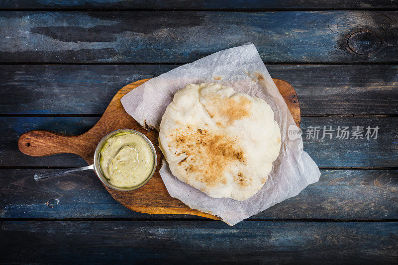 传统的中东开胃菜鹰嘴豆泥配新鲜的皮塔饼。在一块木板上。俯视图