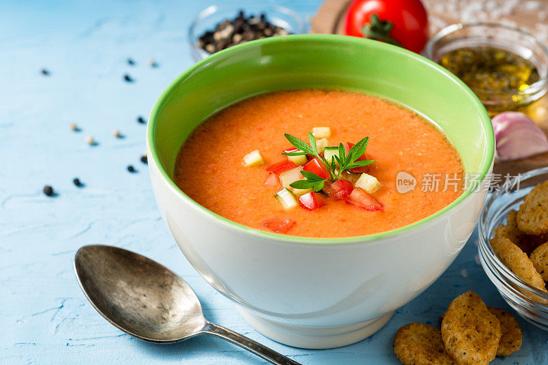 蓝色混凝土背景下的夏季冷汤西班牙凉菜汤。