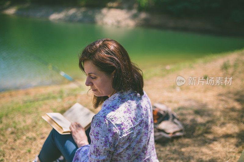 一个年轻女子坐在夕阳下的湖上看书。