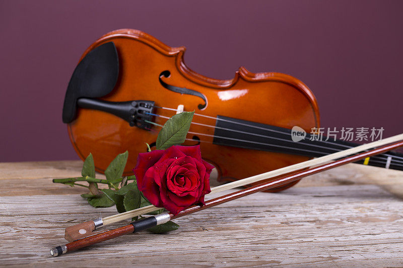 木桌上放着小提琴和红玫瑰