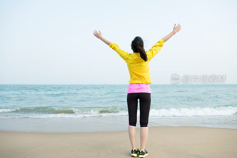 年轻女子在海边举起双手