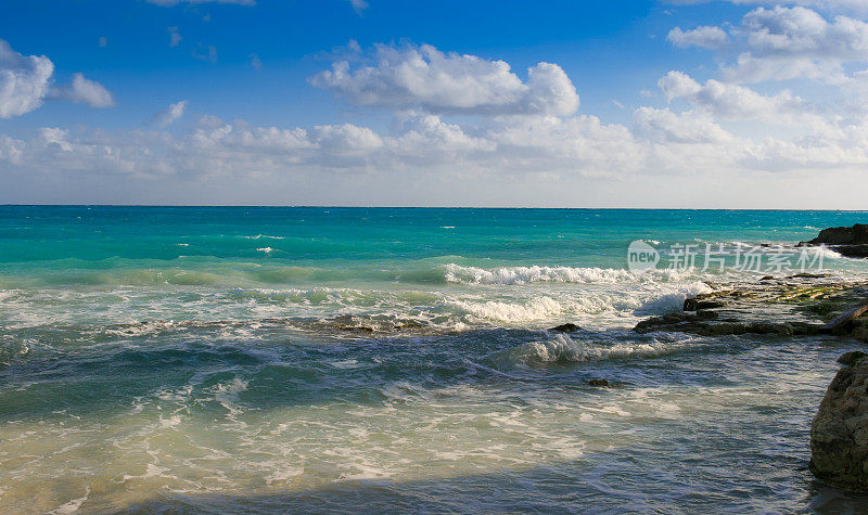 加勒比海与海浪打破海岸，蓝色和蓝绿色的水和蓝色的天空，坎昆，墨西哥。